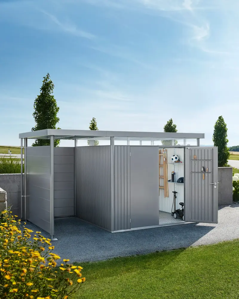 Metalno spremište Biohort HighLine s bočnom nadstrešnicom na šljunčanom prilazu uz vrt