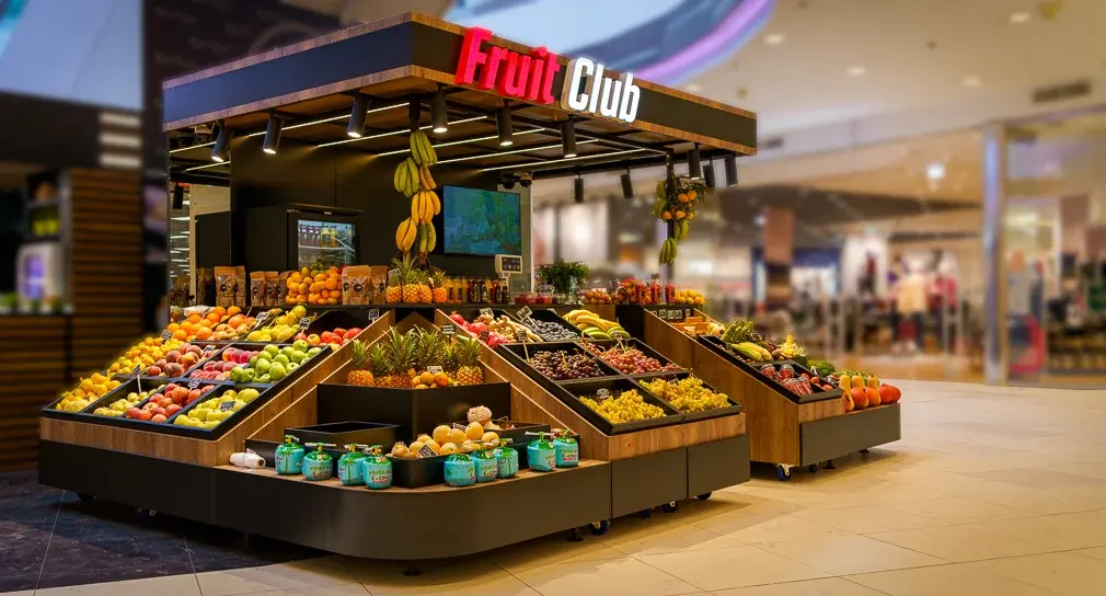 Fruit Club prodajni otok u trgovačkom centru s drvenim policama i natkrivenom konstrukcijom s rasvjetom